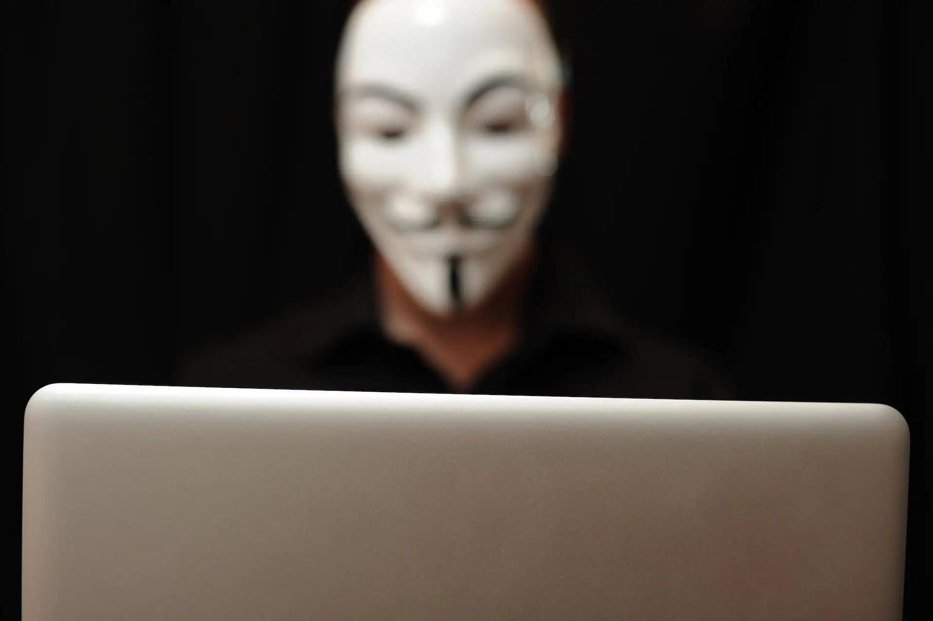 Persona enmascarada con un ordenador portátil